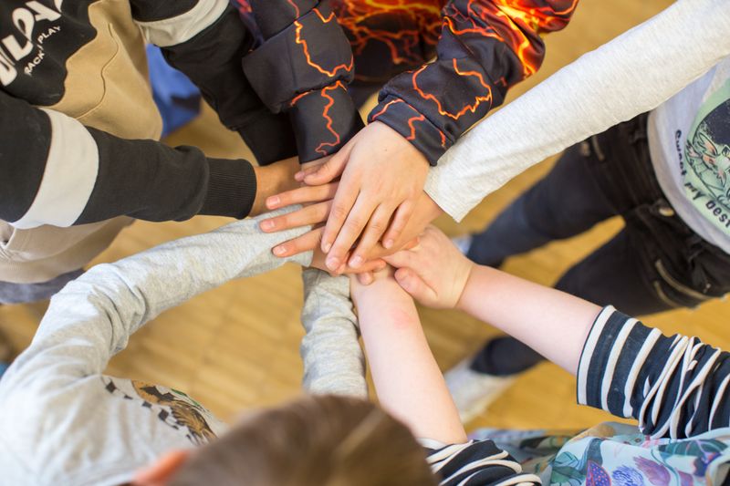 Kinder stapeln ihre Hände bei einer Mediationsübung